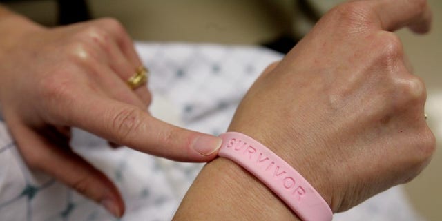 A cancer patient shows off her breast cancer survivor bracelet REUTERS/Jim Bourg