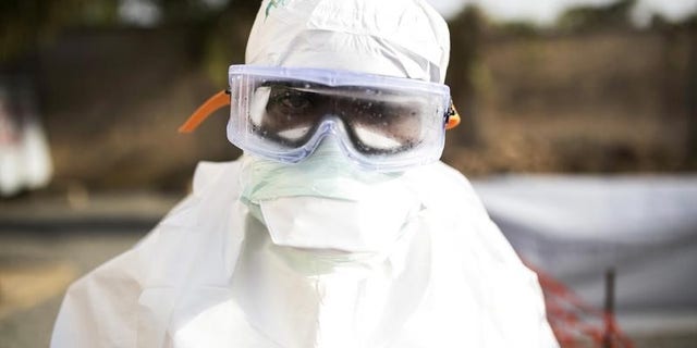A health worker wearing protective gear stands outside a quarantine zone in a Red Cross facility in the town of Koidu, Kono district in Eastern Sierra Leone December 18, 2014. REUTERS/Baz Ratner
