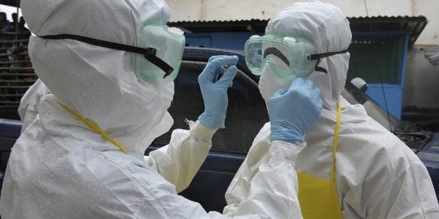 Health workers wearing protective clothing prepare themselves before to carrying an abandoned dead body presenting with Ebola symptoms at Duwala market in Monrovia August 17, 2014. REUTERS/2Tango
