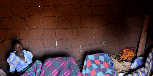 A teenager from Uganda's Sebei tribe sits inside a mud hut after undergoing female genital mutilation in Bukwa district