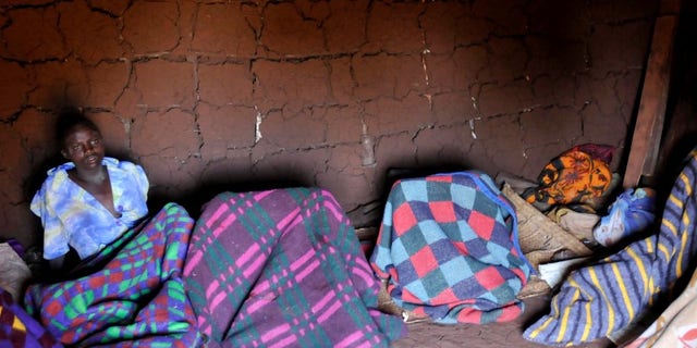 A teenager from Uganda's Sebei tribe sits inside a mud hut after undergoing female genital mutilation in Bukwa district