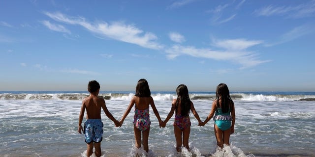 Children walk into the Pacific Ocean in Santa Monica