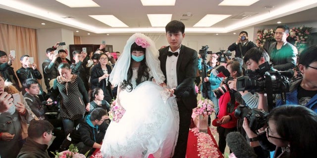 Fan walks on the red carpet with her groom during their wedding at a hospital in Zhengzhou