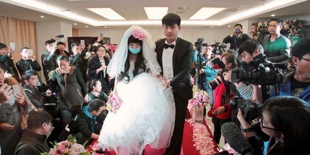 Fan walks on the red carpet with her groom during their wedding at a hospital in Zhengzhou