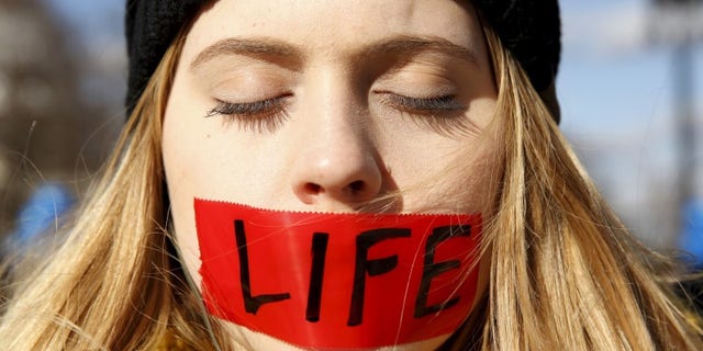 A protester with her mouth taped stands in front of the U.S. Supreme Court in Washington