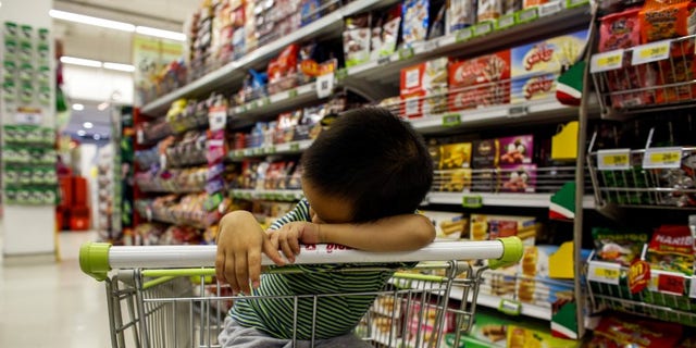 A boy sleeps in a shopping cart at a department store in Bangkok