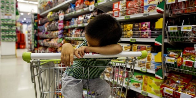 A boy sleeps in a shopping cart at a department store in Bangkok