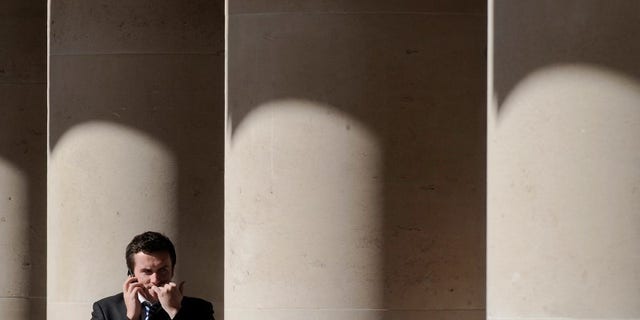 A city worker bites his nails outside the London Stock Exchange in Paternoster Square in the City of London