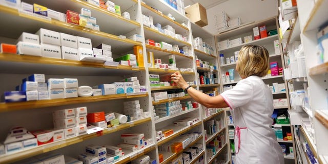 A pharmacist selects drugs inside her pharmacy in Bordeaux