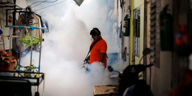 A city worker fumigates the area to control the spread of mosquitoes at a university in Bangkok
