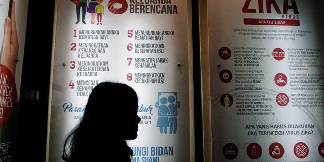 A woman stands near a poster explaining about the Zika virus at the Ministry of Health office in Jakarta