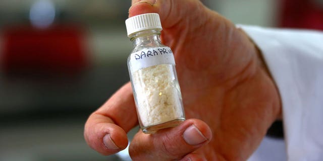 School teacher Dr Malcolm Binns holds a small jar of the compound of an anti-parasitic medicine used to treat malaria, called Daraprim, which was partly made by his students in a lab at Sydney Grammar School in Sydney