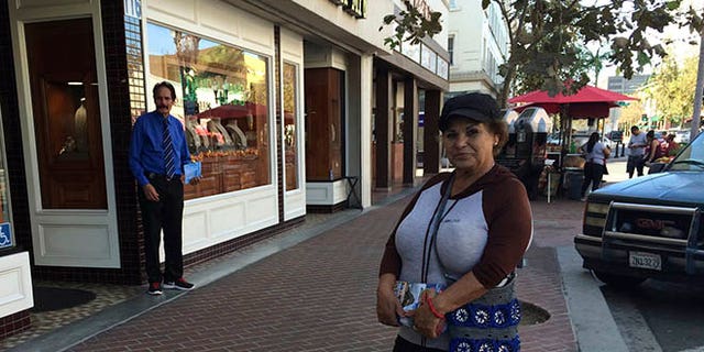 Alicia Ramirez, 67, hands out fliers to passers-by on a busy street in a largely Latino area lined with money transfer businesses and shops selling elegant gowns for quinceanera celebrations, on Wednesday, Nov. 9, 2016, in Santa Ana, Calif. She said she's afraid of what a Trump victory will mean for immigrants like her who lack legal papers. (AP Photo/Amy Taxin)