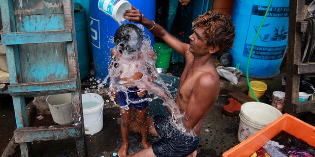 In this May 23, 2016, file photo, a man bath his son on a hot afternoon in a slum in Mumbai, India. For the third straight year, Earth set a record for the hottest year, NOAA and NASA announced.
