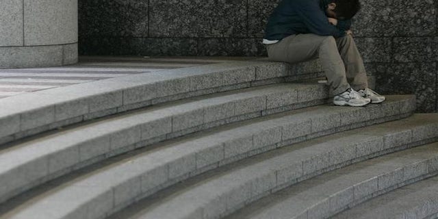 A man sits hunched over on a staircase in Tokyo