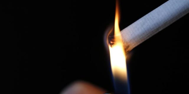 A woman lights a cigarette in this illustration picture taken in Paris