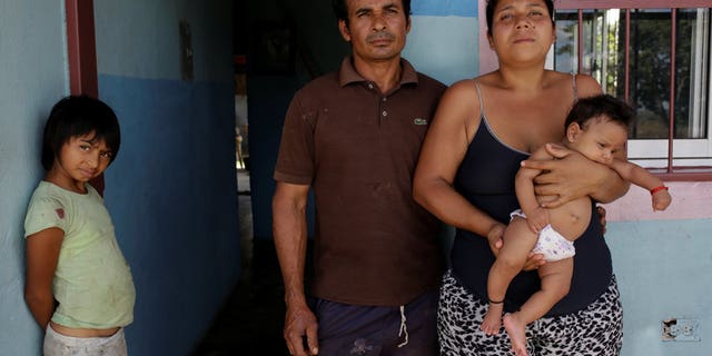 Tulio Medina and Jennifer Vivas, parents of Eliannys Vivas, who died from diphtheria, pose for a photo with two of their children at the front porch of their home in Pariaguan