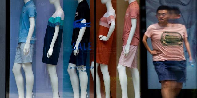 A man walks past mannequins with various fashion design clothes on display at a boutique in Beijing Tuesday, July 14, 2015. China's June export growth rebounded to 2.8 percent in a modest improvement amid slowing economic growth while imports fell 6.1 percent. (AP Photo/Andy Wong)