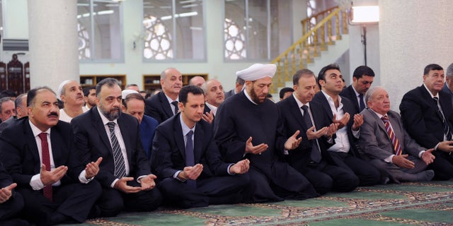 In this photo released by the Syrian official news agency SANA, Syrian President Bashar Assad, third left, prays on the first day of Eid al-Adha at the Sayeda Hassiba mosque, in Damascus, Syria, Tuesday, Oct. 15, 2013. (AP Photo/SANA)