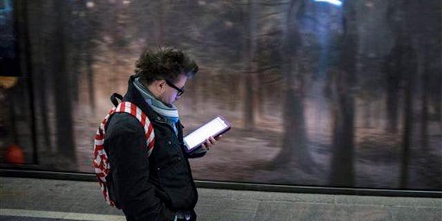 A man surfs the Internet on his tablet in a Moscow subway, Russia, Wednesday, April 8, 2015.