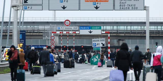 Travellers walk on the highway to the Orly airport, south of Paris, Saturday, March, 18, 2017. A man was shot to death Saturday after trying to seize the weapon of a soldier guarding Paris' Orly Airport, prompting a partial evacuation of the terminal, police said. (AP Photo/Thibault Camus)