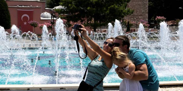 FILE - In this Tuesday, July 26, 2016 file photo, tourists take a selfie at the Byzantine-era Hagia Sophia, in the historic Sultanahmet district of Istanbul. With summer drawing to a close, Turkey is counting the cost of a tough year that saw a string of terrorist bombings and a diplomatic spat with Moscow that cut deep into the country’s crucial tourist trade. (AP Photo/Petros Karadjias, File)
