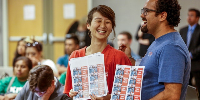 FILE - In this June 24, 2014, file photo, community organizers Lucia Lin, left, and Carlos Amador join about 100 people during a California Department of Motor Vehicles hearing in downtown Los Angeles held to take public comments on proposed rules by which immigrants in the country illegally may obtain driver's licenses. In January, California joins nine other states in allowing immigrants who canât prove theyâre in the U.S legally to get a driverâs license. (AP Photo/Damian Dovarganes, File)