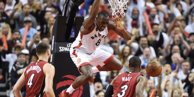 May 15, 2016: Toronto Raptors' Bismack Biyombo (8) dunks over Miami Heat's Dwyane Wade (3) and Josh McRoberts (4) during the second half of Game 7 of the NBA Eastern Conference semifinals in Toronto.