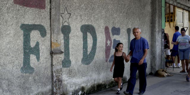 HAVANA, CUBA - AUGUST 12: A man walks in front of a wall that says "Fidel" August 12, 2003 in Old Havana, Cuba. Cuban President Fidel Castro turns 77 August 13, 2003 and has been in power for 44 years, making him the world's longest serving head of state. (Photo by Jorge Rey/Getty Images)