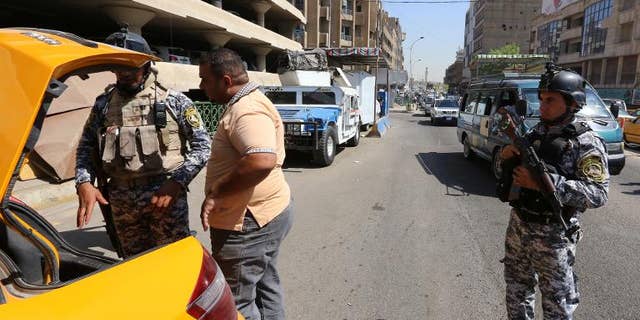 Iraqi security forces search a taxi cab at a mobile checkpoint in Baghdad on August 27, 2013. Car bombs mainly targeting Shiite-majority areas of Baghdad province killed at least 25 people and wounded more than 100 on Monday.