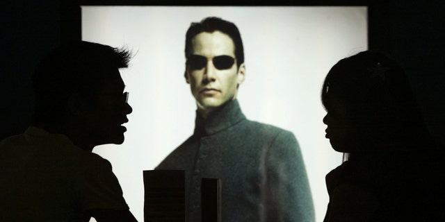 File photo: Chinese movie patrons wait in front of Hollywood star Keanu Reeves poster in the movie Matrix Reloaded showing at Paradise Warner Bros Cinema City in Shanghai July 18, 2003. (REUTERS/Claro Cortes IV)