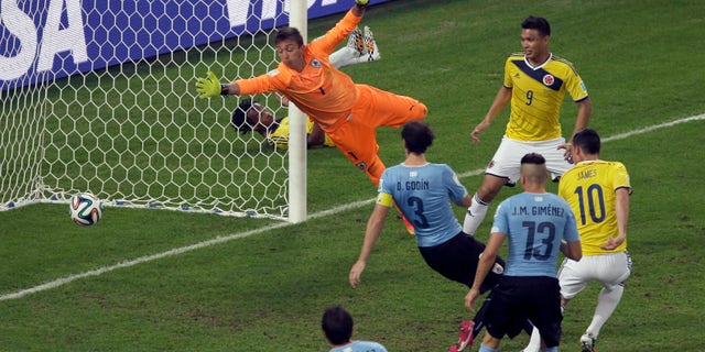 FILE - In this June 28, 2014, file photo, Colombia's James Rodriguez, right, scores his side's second goal past Uruguay's goalkeeper Fernando Muslera during the World Cup round of 16 soccer match between Colombia and Uruguay at the Maracana Stadium in Rio de Janeiro, Brazil. This Colombian team's unselfish poise and muscular grace has let people 'transcend the political tribalism that has defined Colombia's violent history. (AP Photo/Themba Hadebe, File)
