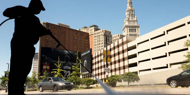 FILE - In this Aug. 5, 2015 file photo, a worker cleans the sidewalk in front of the Quicken Loans Arena in Cleveland. The Labor Department releases its job openings and labor turnover survey for July on Wednesday, Sept. 9, 2015. (AP Photo/Andrew Harnik, File)