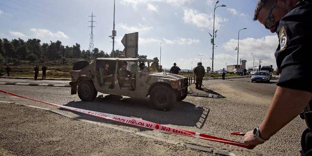 Dec. 1, 2014 - Israeli soldiers and police officers stand at the scene of a stabbing attack at the West Bank Gush Etzion junction near Jerusalem. A Palestinian woman stabbed and slightly wounded an Israeli civilian in the West Bank, the Israeli military said. Eyewitnesses said the attacker involved was shot by security forces in the area and taken for medical treatment.