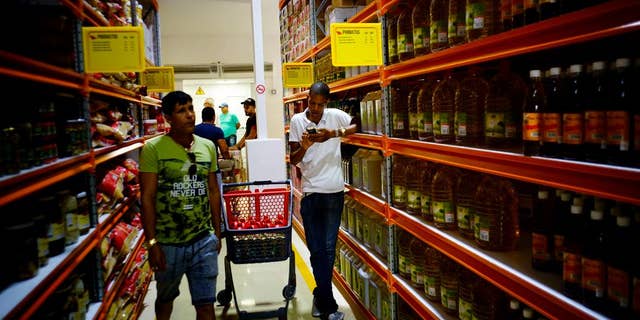 Shoppers walk through the aisles of a new bulk goods store in Havana, Cuba, Monday, July 11, 2016. Called Zona +, the high-ceiling space has racks stacked with large tins of tomato sauce, toilet paper and cooking oil by the gallon. (AP Photo/Ramon Espinosa)