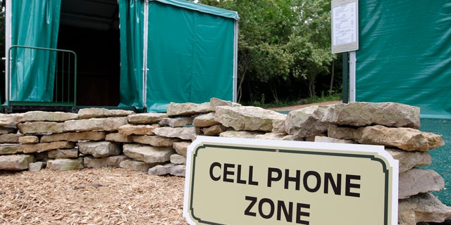 In this photo taken Wednesday, May 22, 2013, a cell phone zone located near a digital hub, left, and concession stand are shown at Muirfield Village Golf Club in Dublin, Ohio. The cell phone zones were created to keep fans' cell phone away from the course and the golfers, while the digital hubs will feature Memorial Tournament social media content and player information to allow fans to have a better experience. (AP Photo/Jay LaPrete)