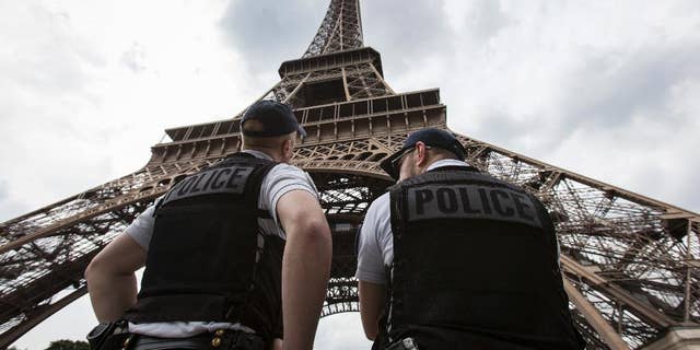 FILE- In this Friday, June 10, 2016 file photo, French riot police officers patrol under the Eiffel Tower, near the entrance of the soccer fan zone, prior to the Euro 2016 Group A soccer match between France and Romania, in Paris. Paris authorities say Thursday, Feb. 9, 2017, they are proposing to replace the metal security fencing around the Eiffel Tower with a more aesthetic glass wall. (AP Photo/Kamil Zihnioglu, File)