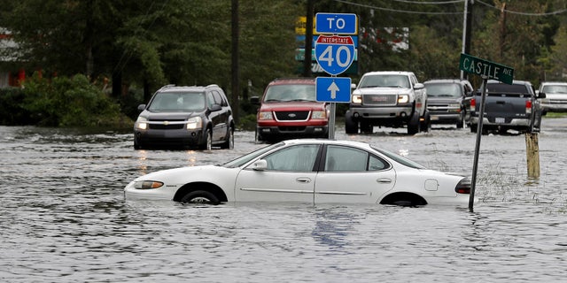 Cars try to navigate a flooded road leading to Interstate 40 in Castle Hayne, North Carolina, after damage from Hurricane Florence cut off access to Wilmington.