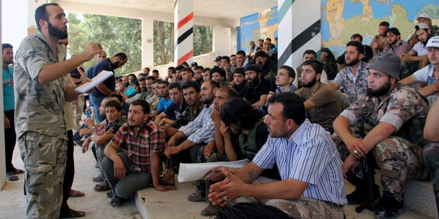 In this Tuesday, Aug. 13, 2013 citizen journalism image provided by Tawhid Brigade, which has been authenticated based on its contents and other AP reporting, Abdul-Qadir Saleh, left, the chief commander of the Tawhid Brigade, the main rebel outfit in Aleppo province, speaks to his fighters ahead of an attack on government troops, in Aleppo, Syria. The Britain-based Syrian Observatory for Human Rights, which relies on a network of activists on the ground, said Friday that a government airstrike the previous night in northern Syria killed a senior rebel figure and wounded two commanders and the spokesman of the Tawhid Brigade. According to the Observatory, the chief commander of the brigade, Abdul-Qadir Saleh, was wounded while the brigade's financial officer, Abu Tayeb, was killed. (AP Photo/Tawhid Brigade)