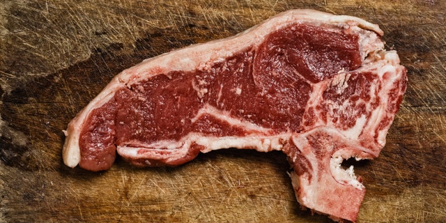 Raw beef steak on cutting table, studio shot.