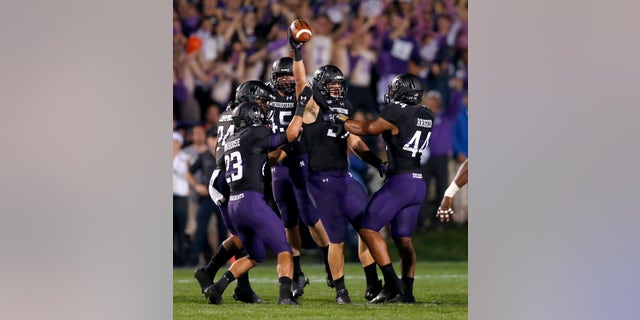 Northwestern defensive lineman Tyler Scott holds the ball up after causing a fumble by Ohio State quarterback Braxton Miller namduring the first half of an NCAA football game Saturday, Oct. 5, 2013, in Evanston, Ill. (AP Photo/Charles Rex Arbogast)