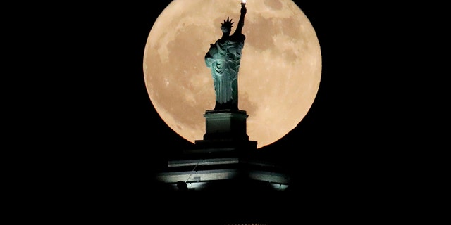 A supermoon stands in front of a replica of the Statue of Liberty sitting on top of the Liberty Building in downtown Buffalo, New York, on Sunday, December 3, 2017. 