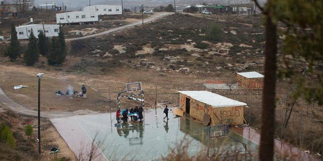 File - In this Sunday, Dec. 18, 2016 file photo, Jewish settlers cook food in a basketball field in Amona, an unauthorized Israeli outpost in the West Bank, east of the Palestinian town of Ramallah. A group of Palestinian landowners is set to reclaim the property they watched stripped from them two decades ago, hoping to finally put to rest a bitter, years-long battle that thrust them into a protracted legal saga and a political crisis that threatened to tear apart Israel's governing coalition. (AP Photo/Oded Balilty, File)