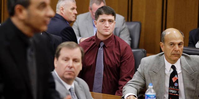 In this Dec. 17, 2014 photo, suspended Cleveland Police patrolman Michael Brelo, center, watches during a court hearing in Cleveland. A motion filed Tuesday, March 10, 2015, asks a Cuyahoga County judge in Cleveland to dismiss two voluntary manslaughter charges against 30-year-old Brelo. The attorneys argue that Brelo is immune from prosecution because he believed his life was in danger when he jumped on the hood of the suspects’ car and fired as many as 15 rounds through the windshield following a high-speed chase in November 2012. (AP Photo/Tony Dejak)