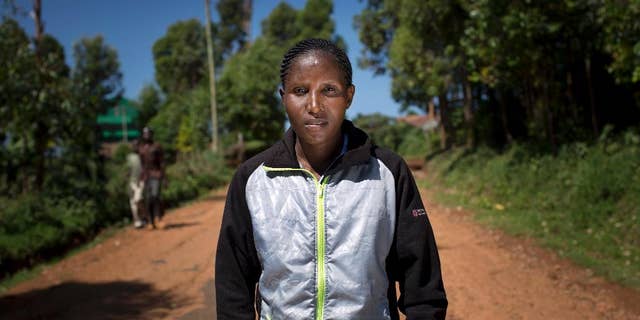 In this Monday, Feb. 1, 2016, photo, Kenyan runner Lilian Mariita poses for a portrait on the dirt road outside her house in the village of Nyaramba in western Kenya. The 27-year-old's racing career is over, and now she is back at square one: in Nyaramba, the muddy tea-plantation village in western Kenya she thought she'd escaped in 2011, when she left for the promise of a new life pounding American roads. (AP Photo/Ben Curtis)