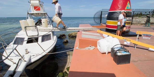 Environmental clean-up crews respond to a grounded dive boat that contained a group of Cuban migrants on Wednesday, July 13, 2016, at the Southermost Point marker in Key West, Fla. The group of three men and three women were taken into custody on Duval Street shortly thereafter and will be processed at the Krome Detention Center in Miami. (Rob O'Neal(/The Miami Herald via AP)(/The Key West Citizen via AP) MIAMI OUT; MANDATORY CREDIT