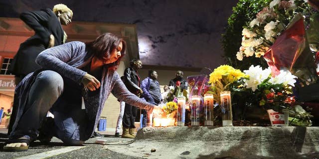 Tricia Dennis and Orlando city commissioner Regina Hill, far left, pay their respects at a makeshift memorial to honor an Orlando police sergeant killed Monday at the parking lot of a Wal-Mart store and an Orange County Sheriff's Office deputy before a candlelight vigil at the store in Orlando, Fla., Tuesday, Jan. 10, 2017. (Joe Burbank/Orlando Sentinel via AP)