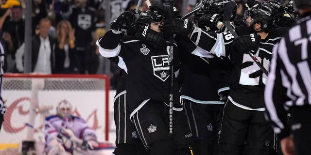 Members on the Los Angeles Kings, right, celebrates a game-winning goal by right wing Dustin Brown as New York Rangers goalie Henrik Lundqvist, left, of Sweden, looks on in the second overtime period in Game 2 of the NHL hockey Stanley Cup Finals, Saturday, June 7, 2014, in Los Angeles. The Kings won 5-4. (AP Photo/Mark J. Terrill)