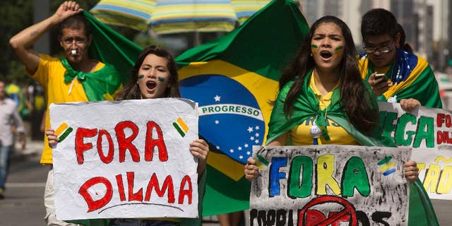 Demonstrators shout anti-government slogans as they march holding signs that reads in Portuguese "Dilma Out" and "Corrupt Out", during a protest demanding the impeachment of Brazil's President Dilma Rousseff in Sao Paulo, Brazil, Sunday, April 12, 2015. It was the second such day of protests in less than a month and comes as polls show Rousseff with historically low approval ratings amid a corruption scandal at the state-run oil company, Petrobras, as well as a spluttering economy, a rapidly depreciating currency and political infighting. (AP Photo/Andre Penner)