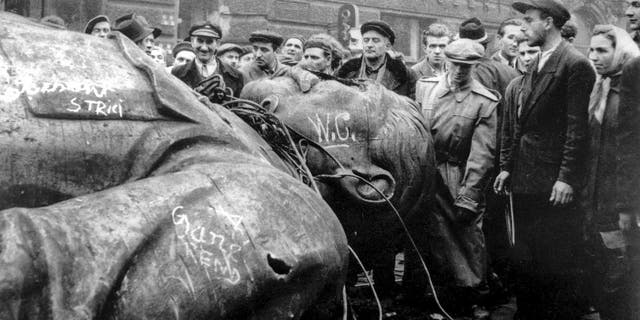 In this Oct. 24, 1956 file photo, people gather around a fallen statue of Soviet leader Josef Stalin in front of the National Theater in Budapest, Hungary. The uprising in Hungary began on Oct. 23, 1956 with demonstrations against the Stalinist regime in Budapest and was crushed eleven days later by Soviet tanks amid bitter fighting. For Hungary, a pro-Russian leader in the White House offers hope the Western world might end the sanctions imposed over Russia’s annexation of Crimea and its role in eastern Ukraine. Many Poles, instead, fear a U.S-Russian rapprochement under Trump could threaten their own security interests. To most Poles, NATO represents the best guarantee for an enduring independent state in a difficult geographical neighborhood.